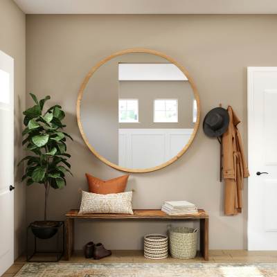 light wood flooring in entry way with area rug, bench, and large circular mirror.